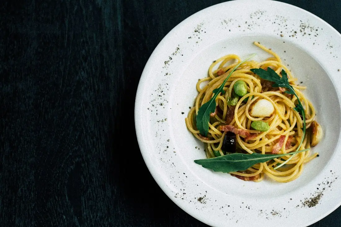 Pasta with greens and olives on a speckled plate