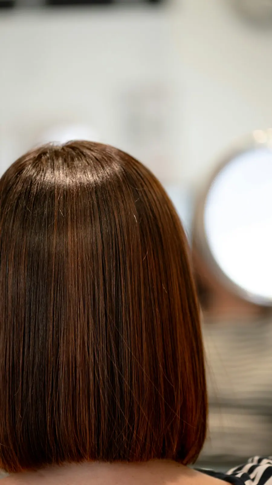 A sharp chin-length chestnut bob, seen from behind